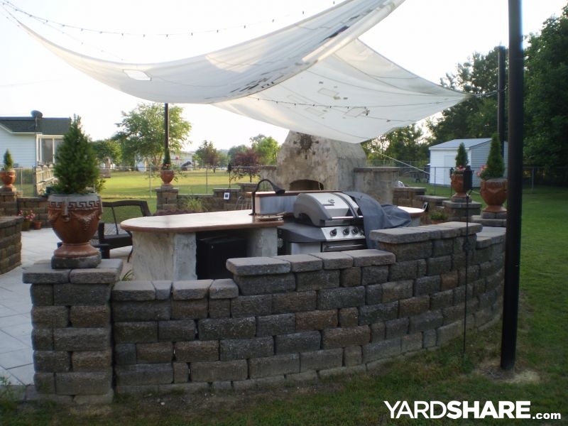 Patio fireplace with stone walls and grilling island